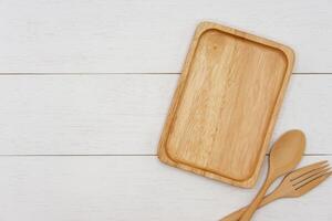 Empty rectangle wooden plate with spoon and fork on white wooden table. Top view image. photo