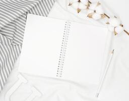 blanco blanco espiral cuaderno con blanco lápiz en cama. foto