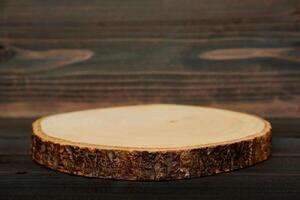 Empty rustic wooden slice serving board on dark brown wooden table. photo