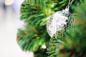 Closeup image of silver mirrored mosaic Christmas ornament hanging on Christmas tree. photo