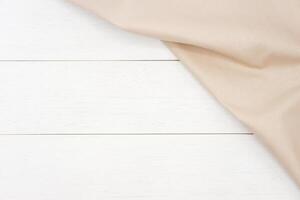 Wrinkled beige fabric on rustic white wood plank background, with copy space. photo