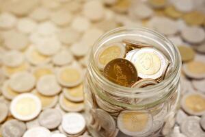 Close-up image of a glass jar full of new Thai baht coins. Business and finance concept. photo