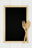 Blank chalkboard with wooden spoon and fork on white wood plank background. Styled stock photography for cookbook, food blog posts and social media content. photo
