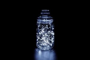 White fairy light in a glass jar, in the dark, low-key photography photo