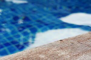 vacío rústico de madera mesa en frente de borroso antecedentes de nadando piscina. foto