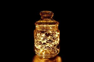 Fairy Light in a Glass Jar with Wooden Lid, in the Dark. Low-Key Photography. photo