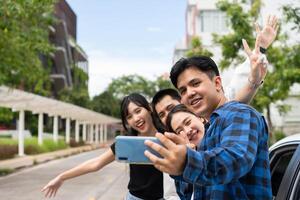 grupo de contento joven asiático estudiantes selfies y videos con teléfonos inteligentes juntos para vlog y social medios de comunicación en verano vacaciones. concepto de turismo y viaje y la carretera viaje, amistad estilo de vida. foto