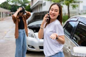 Asian women driver check for damage after a car accident before taking pictures and sending insurance. Online car accident insurance claim after submitting photos and evidence to an insurance company.