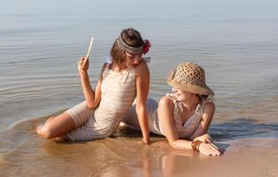 Two young women in retro swimsuits by the sea photo
