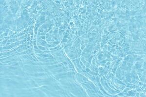 Water surface. Bluewater waves on the surface ripples blurred. Defocus blurred transparent blue colored clear calm water surface texture with splash and bubbles. Water waves with shining pattern. photo