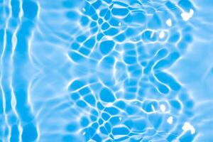 Water surface. Bluewater waves on the surface ripples blurred. Defocus blurred transparent blue colored clear calm water surface texture with splash and bubbles. Water waves with shining pattern. photo