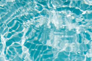 Water surface. Bluewater waves on the surface ripples blurred. Defocus blurred transparent blue colored clear calm water surface texture with splash and bubbles. Water waves with shining pattern. photo