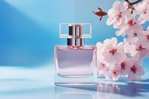 AI generated Glass elegant perfume bottle mockup on blue background with sakura blossom flowers. Glamour advertisement banner, copy space. photo