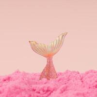 Creative trendy layout made with mermaid diving into pink sand against peachy pink background. Minimal summer concept. Fancy magical summer beach idea. Fantasy mermaid composition. photo
