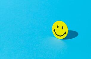 Creative layout made with smiley face sticker on blue background. Minimal positive thinking and good mood concept. Mental health care recovery to happiness emotion. Copy space. photo