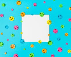 Colorful pattern composition made with smiley face stickers on blue background. Minimal positive thinking and good mood concept. Mental health care recovery to happiness emotion. Flat lay. Copy space. photo