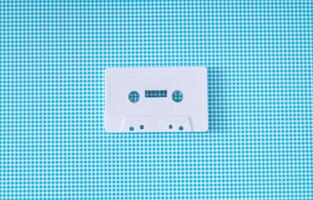 Layout of retro white audio cassette tape on white and blue background. Creative concept of old technology. 80's aesthetic. Vintage audio cassette tape idea. Retro fashion nostalgia. Retro futurism. photo
