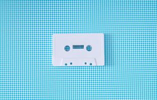 Layout of retro white audio cassette tape on white and blue background. Creative concept of old technology. 80's aesthetic. Vintage audio cassette tape idea. Retro fashion nostalgia. Retro futurism. photo