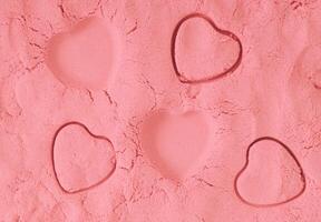 Romantic background composition made with heart shape on peachy pink sand. Minimal love concept. Fancy background and texture idea. Trendy color flat lay. Love aesthetic backdrop. photo
