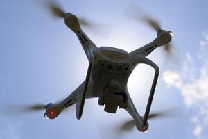 Drone DJI Phantom 4 in flight. Quadrocopter against the blue sky with white clouds. The flight of the copter in the sky. photo