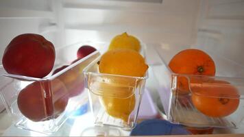 plastic containers with different fruits in a open fridge. video