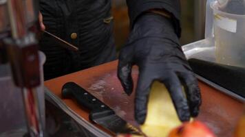 hand in black gloves cutting pineapple on a chopping board at street video