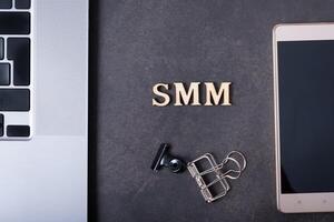 Abbreviation SMM made with wooden letters and phone, laptop. Social Media Marketing concept photo