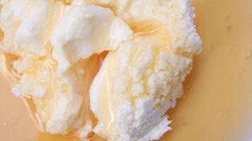 butter cream and honey in a bowl on table . video