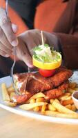 vertical Disparo de mujer comiendo pollo chuleta de ternera servido con patata papas fritas video