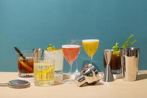 Composition with alcoholic cocktails on podiums and bar tools on colored background. photo