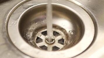 Leaking faucet leaves droplets of water in big silver sink. Water flowing from loosely closed faucet and lasting small drops in sink in kitchen video