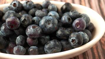 dichtbij omhoog van vers blauw BES in een kom Aan tafel video