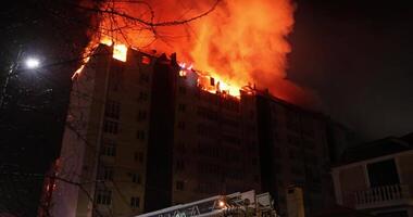 Huge fire blazing in apartment house building. House is engulfed in flames at night during the disastrous video