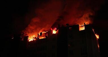 reusachtig brand laaiend in woon- gebouw. huis is overspoeld in vlammen Bij nacht gedurende de rampzalig video