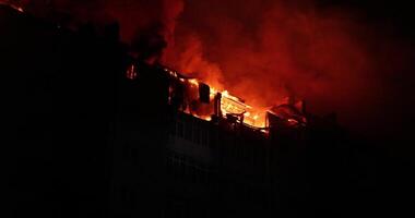 Huge fire blazing in residential building. House is engulfed in flames at night during the disastrous video