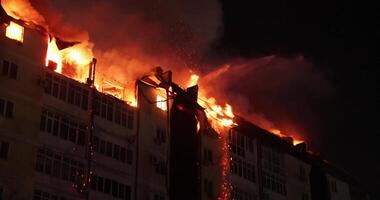 enorme fuego flameante en residencial edificio. casa es envuelto en llamas a noche durante el desastroso video