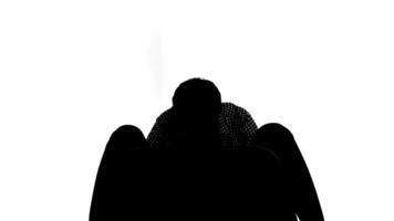 silueta de un persona sentado con cabeza en manos en contra un blanco fondo, representando tristeza o depresión. video