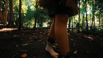 avvicinamento di spoglio piedi a piedi nel un' illuminata dal sole foresta, evidenziazione un' connessione con natura. video
