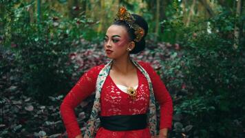 tradicional bailarín en rojo disfraz posando en un lozano bosque ajuste. video