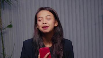 retrato de un joven mujer con cerrado ojos y un alegre expresión, participación un inteligente teléfono video
