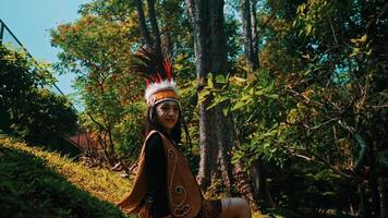 Portrait of a woman in traditional attire with a feathered headdress in a lush forest setting. video