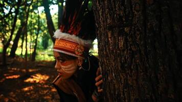 persona propensión en contra un árbol en un bosque durante otoño, con luz de sol filtración mediante el hojas. video