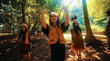 Group of people in traditional attire performing in a forest setting. video