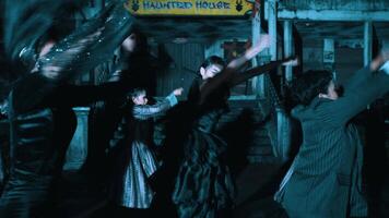 Dancer in black performing at a spooky haunted house attraction with onlookers in the background video