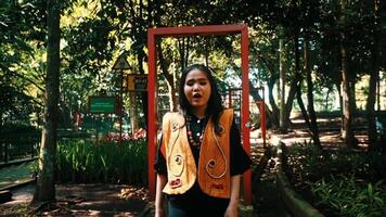 Stylish woman posing in a park with a red frame, surrounded by lush greenery. video