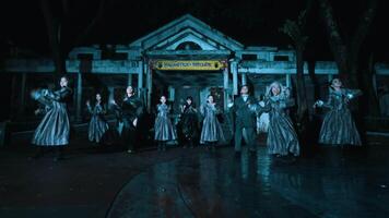 Group of people in period costumes dancing at night in front of a vintage building with illuminated signage. video