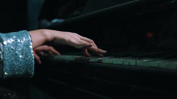 Close-up of a person's hands playing an old piano with visible wear on the keys, in a dimly lit room. video