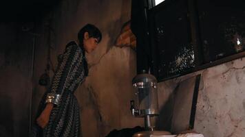 mujer en Clásico vestir en pie por un Anticuado proyector en un rústico habitación. video