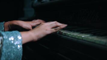 Close-up of a person's hands playing an old piano with visible wear on the keys, in a dimly lit room. video