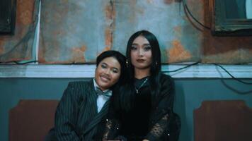 Two women sitting together, smiling, with a vintage wall background. video